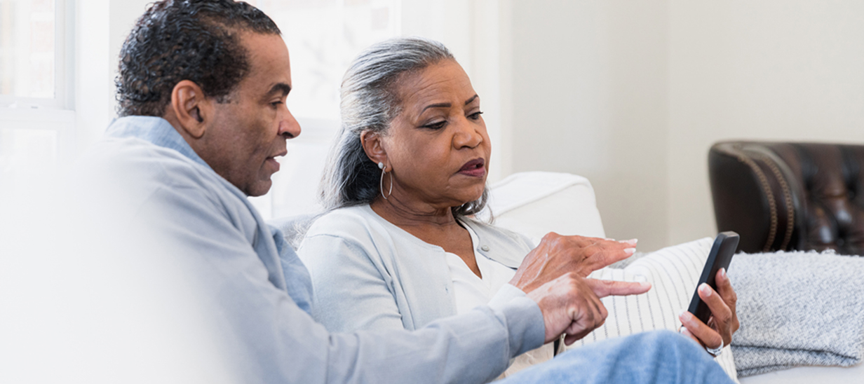 couple âgé regardant l'écran d'un téléphone avec inquiétude