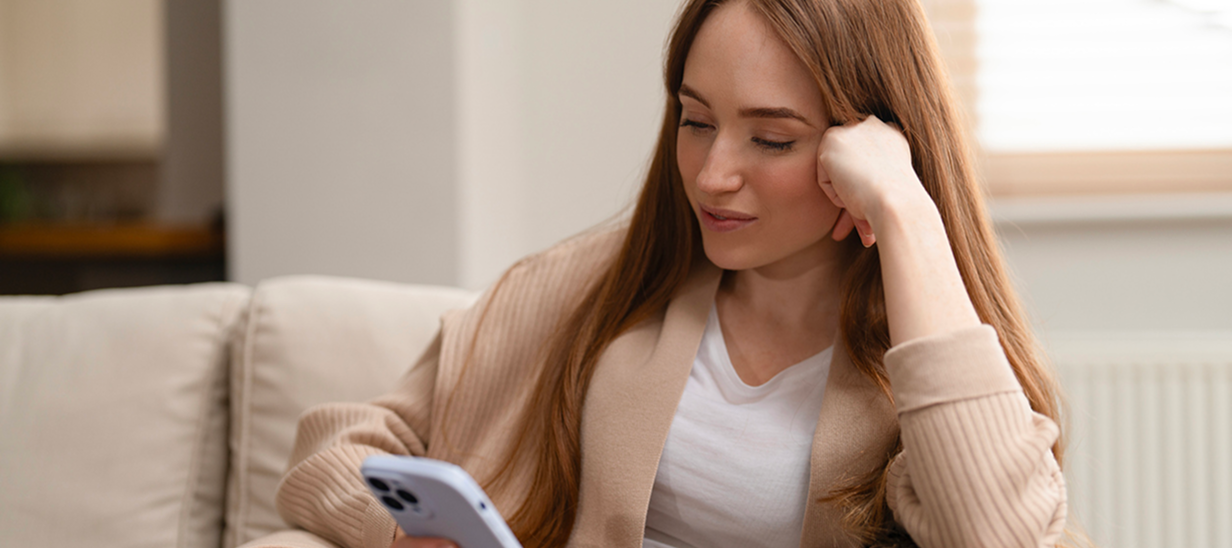 Jeune femme regardant son téléphone alors qu'elle est assise sur un canapé