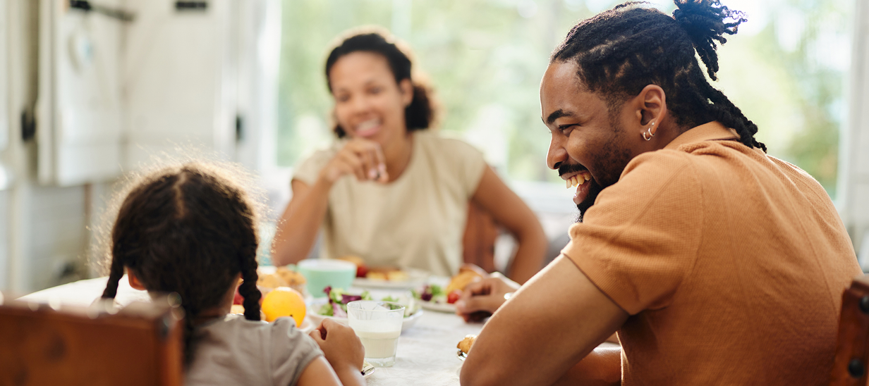 Jeune famille souriante assise autour de la table du dîner